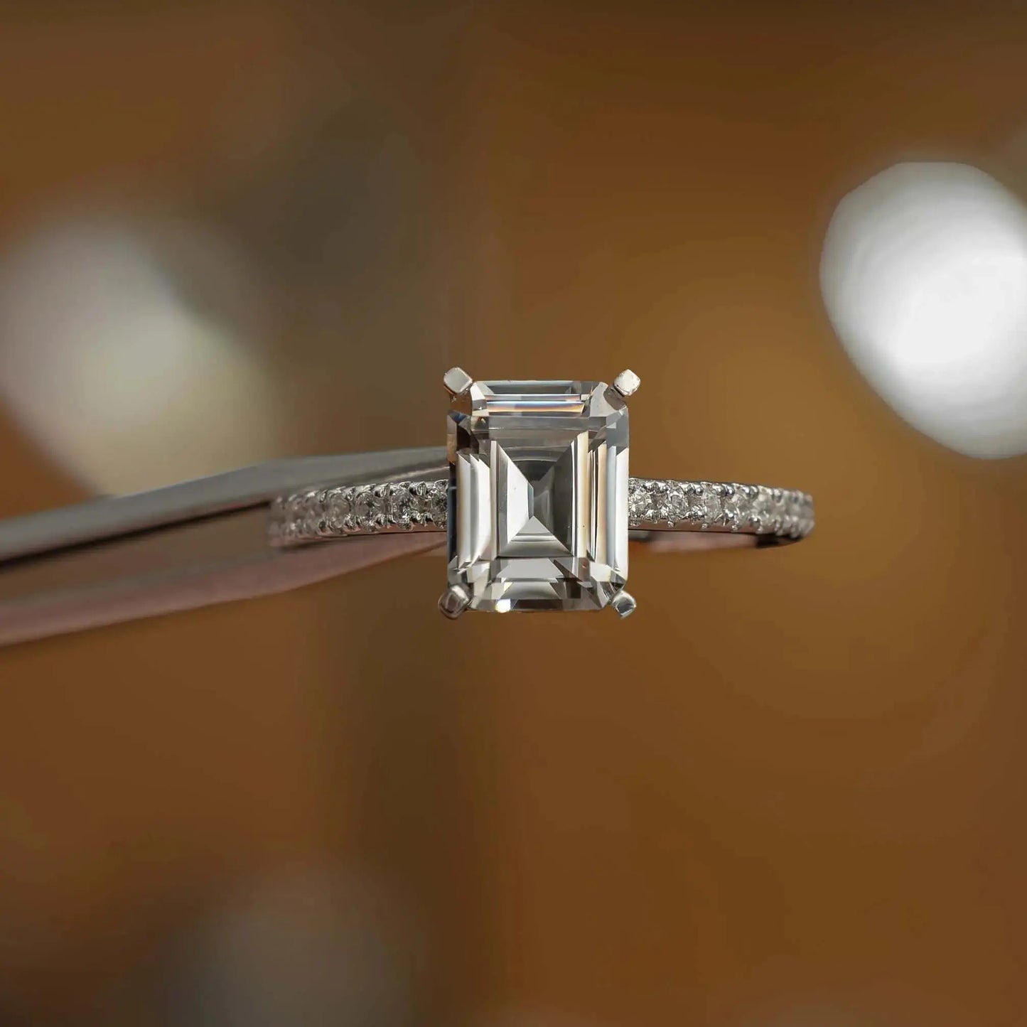 frontal view in studio of luxury emerald platinum diamond set shoulders lab grown diamond engagement ring
