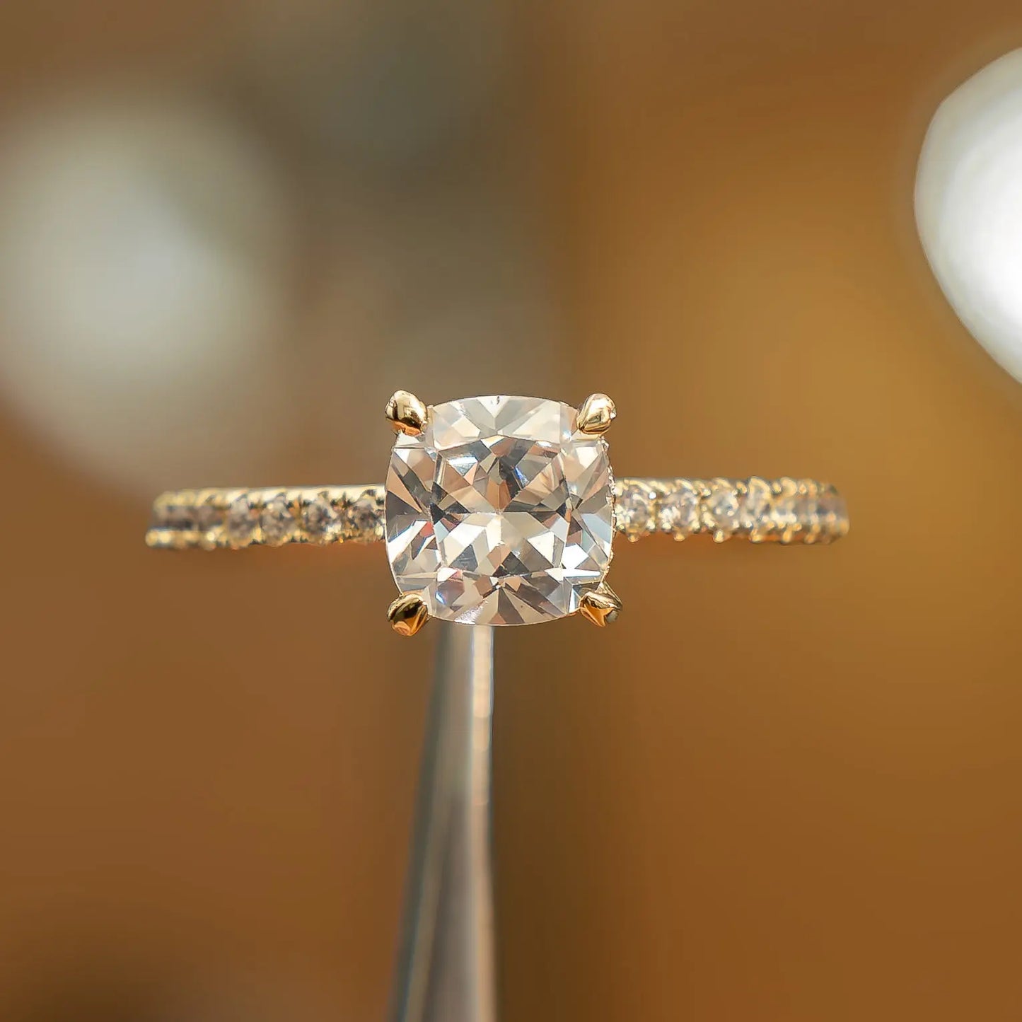 frontal view of luxury cushion yellow gold diamond set shoulders hidden halo lab grown diamond engagement ring