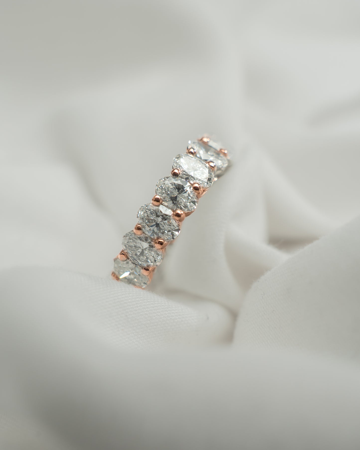 Diamond ring with rose gold setting on a light gray background