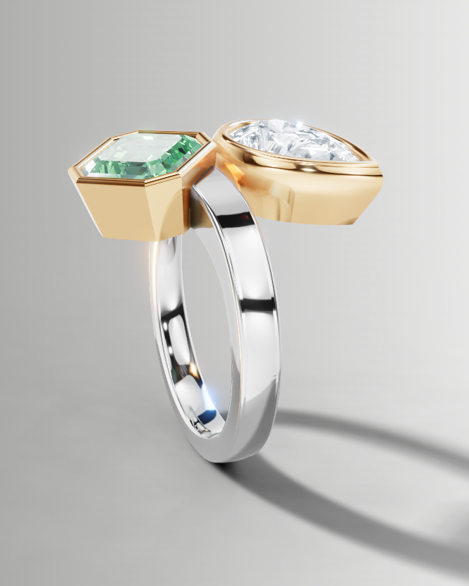 A sculptural two-stone ring featuring a yellow gold hexagonal setting with a green emerald-cut gemstone and a silver-toned band with a clear round-cut gemstone, shown on a neutral gray background.