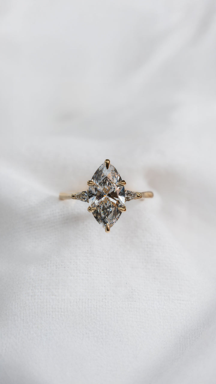Gold ring with two large diamonds on a white fabric background