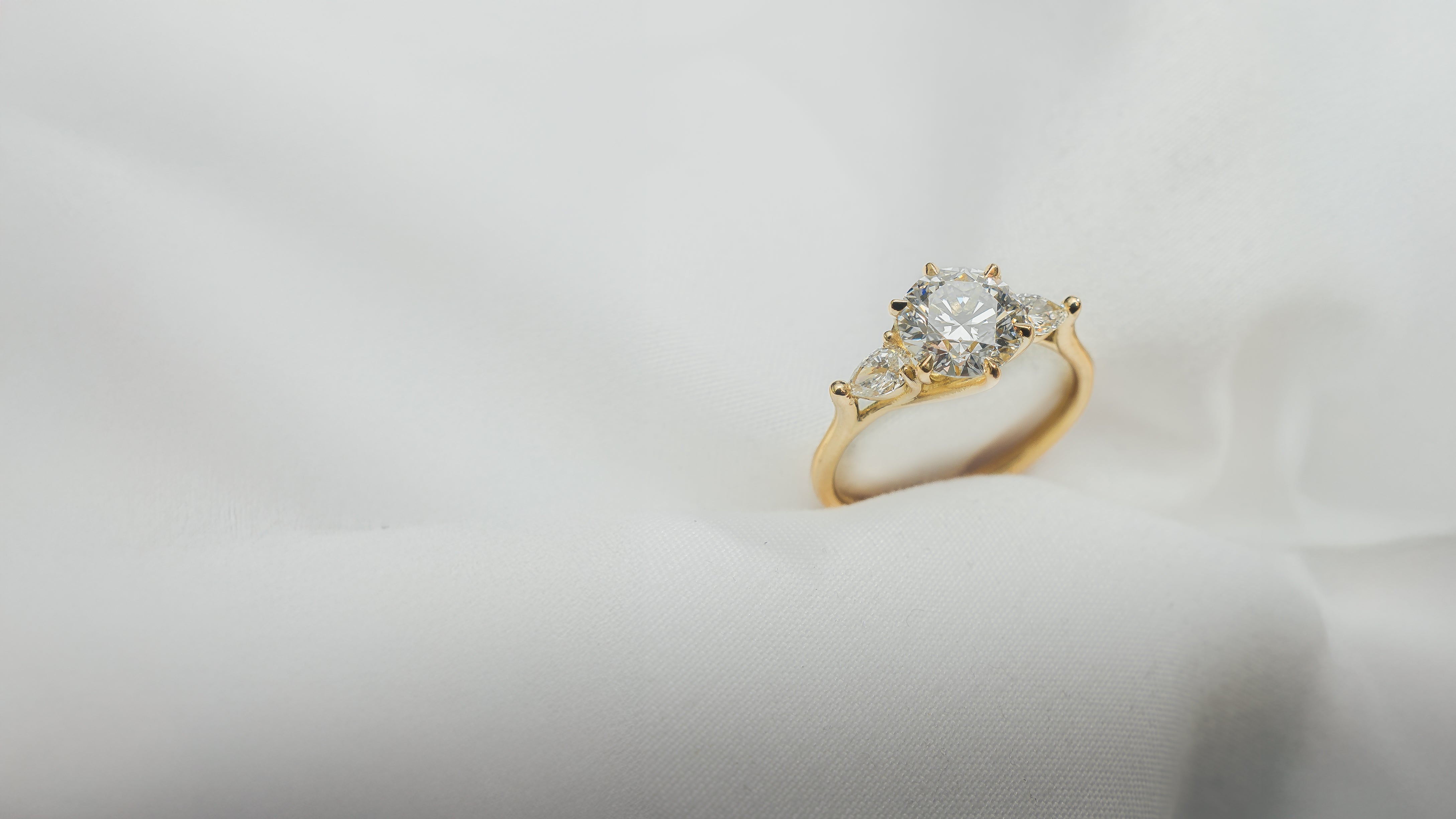 Gold ring with a diamond on a light gray background