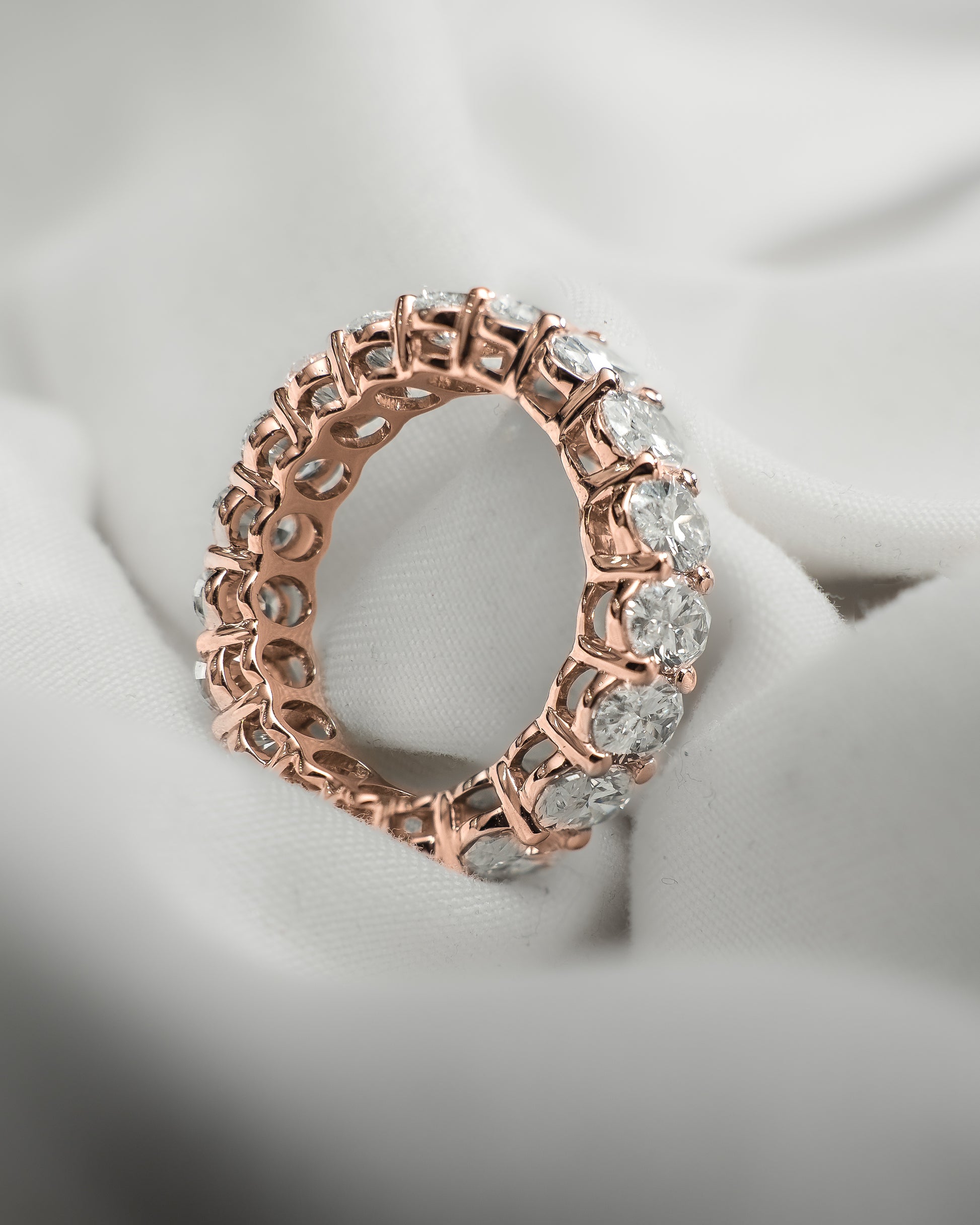 Rose gold ring with diamonds on a soft fabric background