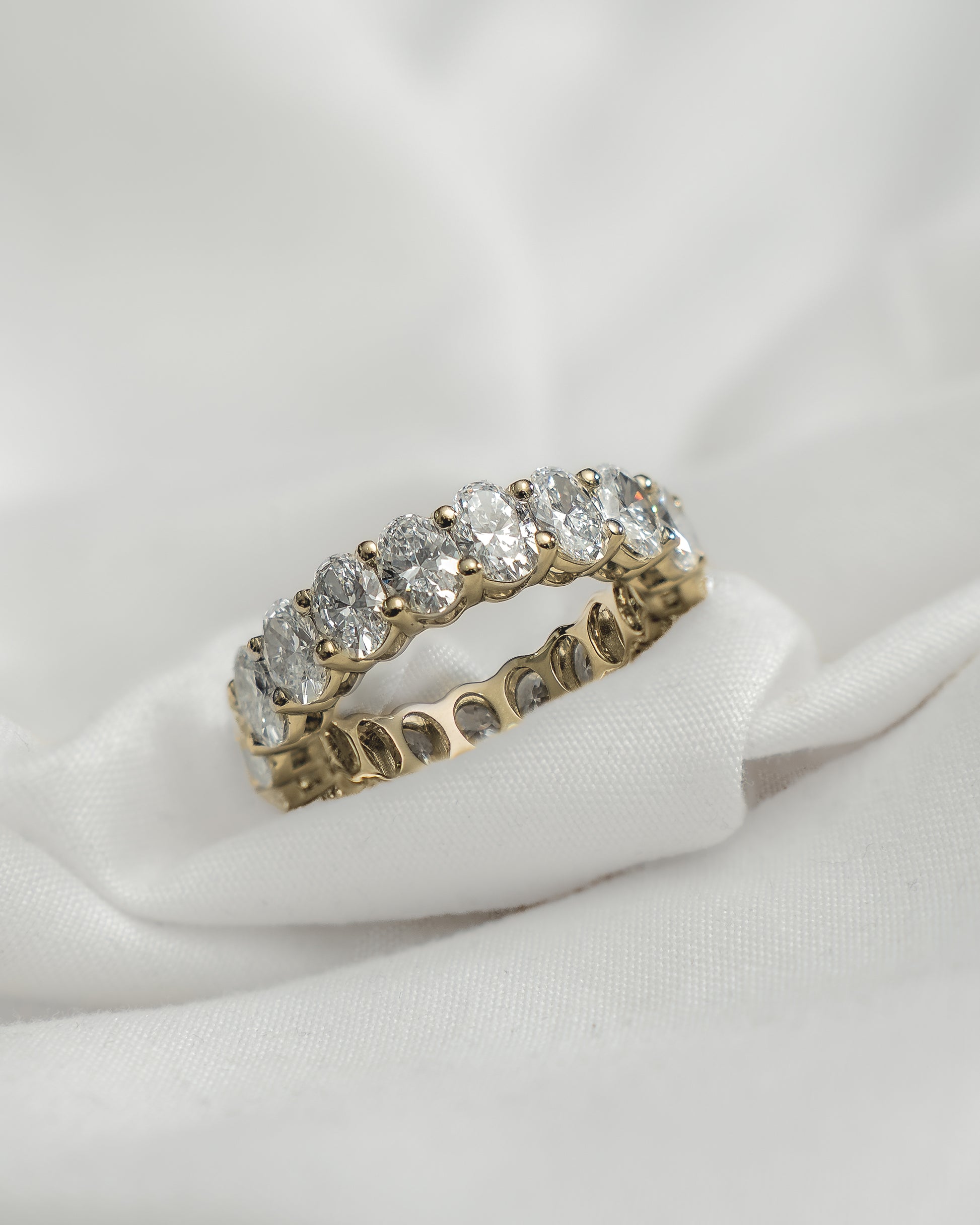 Gold ring with diamonds on a white fabric background