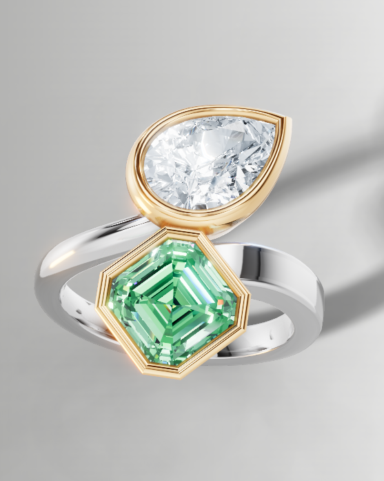 A silver and gold ring featuring a marquise-cut clear gemstone and a green emerald-cut gemstone, shown on a neutral gray background with a soft shadow.
