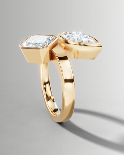 A gold ring featuring two diamond-cut geometric settings on a smooth, polished band, shown against a neutral gray gradient background.