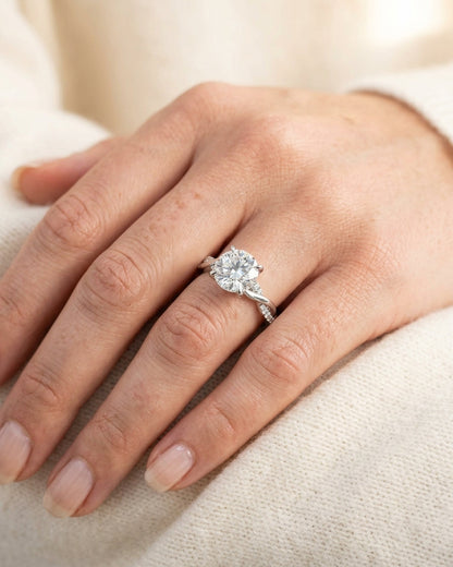 Close-up of a hand wearing a diamond ring on a light background