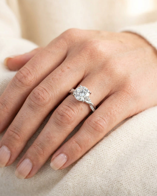 Close-up of a hand wearing a diamond ring on a light background