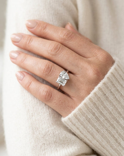 Hand wearing a diamond ring with a neutral background