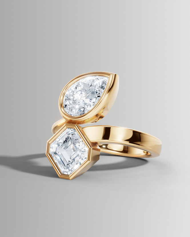 A gold ring featuring two marquise-cut clear gemstones in separate bezel settings, displayed on a clean light gray background.